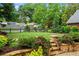 Manicured backyard featuring stone retaining wall, mature trees, lush green lawn, and black picket fence at 574 Chicasaw Ne Dr, Marietta, GA 30060