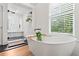 Bright bathroom features a soaking tub next to large windows and a glass-enclosed shower with seating at 574 Chicasaw Ne Dr, Marietta, GA 30060