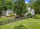 Landscaped yard surrounds gray home with fenced yard, mature shade tree, and rear view of home at 574 Chicasaw Ne Dr, Marietta, GA 30060