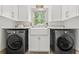 Well-organized laundry room with white cabinetry, sink, and modern washer/dryer at 574 Chicasaw Ne Dr, Marietta, GA 30060