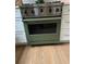 Close-up of a stainless steel oven with a green door and wooden floors at 574 Chicasaw Ne Dr, Marietta, GA 30060