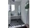 Modern walk-in shower with white tile, glass door, and black and white patterned floor at 574 Chicasaw Ne Dr, Marietta, GA 30060