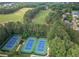Community aerial featuring a golf course, lake, tennis courts, and luxurious homes surrounded by lush greenery at 8340 Colonial Pl, Duluth, GA 30097