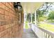 View of covered front porch with wood decking, brick siding, and white railing at 3112 Calumet Nw Cir, Kennesaw, GA 30152