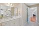 Bright bathroom featuring double vanity with white cabinets, a large mirror, and access to additional space at 405 Branch Forest Way, Stockbridge, GA 30281
