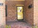 Close-up of brick front porch with tiled flooring, yellow door, and manicured landscaping at 871 Malcom Se St, Conyers, GA 30012