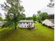 Aerial view of a home with a big backyard featuring a patio, grass, and mature trees at 1444 Elliotts Lane, Auburn, GA 30011