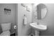 Modern half bathroom with a decorative mirror, white vanity and toilet, enhanced by elegant decor at 1630 Marsanne Nw Ter # 27, Kennesaw, GA 30152