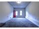 Basement living room featuring red door, window, and gray carpeting at 5904 Heatherwood Ln, Riverdale, GA 30296
