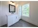 Bright bathroom featuring a white vanity, framed mirror, and a window providing natural light and view of the tree outside at 1197 Avondale Se Ave, Atlanta, GA 30312