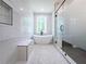 Stylish bathroom with marble walls, freestanding tub, glass shower, and a bright window offering natural light at 1197 Avondale Se Ave, Atlanta, GA 30312