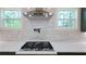 Modern range hood and gas cooktop with white countertop and marble backsplash at 1197 Avondale Se Ave, Atlanta, GA 30312