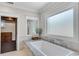 Bright bathroom featuring a soaking tub, frosted windows, and marble countertops at 212 Fernwood Pl, Woodstock, GA 30188