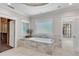 Bright bathroom featuring a tiled soaking tub, large window, and closet, creating a peaceful and functional space at 212 Fernwood Pl, Woodstock, GA 30188