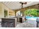Outdoor kitchen and bar area overlooking a pool with water slide and lush landscaping at 212 Fernwood Pl, Woodstock, GA 30188