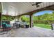 Covered outdoor living area with stone columns, comfortable seating, and access to lush backyard at 212 Fernwood Pl, Woodstock, GA 30188