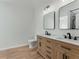 Bright bathroom featuring a double vanity with black hardware, dual mirrors, and wood-look flooring at 3285 Country Walk Dr, Powder Springs, GA 30127