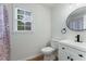 Half bathroom featuring a white vanity with black hardware, a circular mirror, and wood-look floors at 3285 Country Walk Dr, Powder Springs, GA 30127