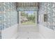 Bright bathroom featuring a jacuzzi tub, blue floral wallpaper, and a window overlooking the backyard at 3472 Honeycomb Se Dr, Conyers, GA 30094