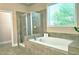 Serene bathroom featuring a soaking tub, glass shower, and large window, creating a peaceful ambiance at 4024 Broadmoor Sw Ct, Austell, GA 30106