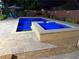 View of the lit in-ground pool and hot tub at night surrounded by concrete pavers and a privacy fence at 4024 Broadmoor Sw Ct, Austell, GA 30106
