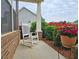 Relaxing porch featuring a white rocking chair, garden view, and brick support columns at 4024 Broadmoor Sw Ct, Austell, GA 30106