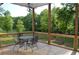 A shaded outdoor deck with a black metal table and chairs overlooking a wooded yard at 8 Ripplewood Trl, Euharlee, GA 30145