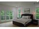 Bright bedroom features a tufted headboard, hardwood floors, and large windows showcasing a lush green view at 8 Ripplewood Trl, Euharlee, GA 30145