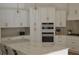 Modern white kitchen with an island, stainless steel appliances and marble countertops and backsplash at 8 Ripplewood Trl, Euharlee, GA 30145