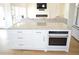 Kitchen island with white cabinets, stainless steel oven, and marble countertop, adjacent to living room at 8 Ripplewood Trl, Euharlee, GA 30145