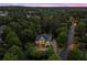 A beautiful aerial view of a well-lit home nestled among trees with manicured landscaping and a paved driveway at 1200 Bay Pointe Terr Ter, Alpharetta, GA 30005