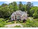 A stunning front elevation of a brick home with manicured landscaping, mature trees, and a circular driveway at 1200 Bay Pointe Terr Ter, Alpharetta, GA 30005