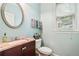 Powder room featuring a mahogany vanity, a marble countertop, a round mirror, and a window with blinds at 1210 Magnolia Park Cir, Cumming, GA 30040