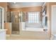 Bright bathroom featuring a soaking tub, glass shower, and neutral-toned tiling at 1210 Magnolia Park Cir, Cumming, GA 30040