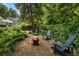 Tranquil backyard features a firepit with Adirondack chairs, blending outdoor living with the beauty of nature at 11355 Bowen Rd, Roswell, GA 30075