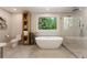 Bright bathroom boasts a modern tub, glass shower, and a serene outdoor view at 11355 Bowen Rd, Roswell, GA 30075