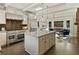 Large kitchen with granite island, stainless appliances, white cabinets, and sunroom adjacent to the dining area at 11355 Bowen Rd, Roswell, GA 30075