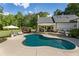 An in-ground pool with an open patio, an umbrella-covered lounge area, and a covered patio for outdoor dining at 11355 Bowen Rd, Roswell, GA 30075