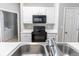Close-up of a stainless steel kitchen sink with white countertops and modern fixtures with appliances nearby at 1731 Pryor Sw Rd # 109, Atlanta, GA 30315