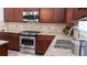 This kitchen features stainless steel appliances, granite countertops, a tiled backsplash, and dark wood cabinets at 760 King Sword Ct, Mableton, GA 30126