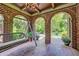 Relaxing brick porch with swing, tiled floor, arched openings, and serene outdoor views at 1356 Emory Ne Rd, Atlanta, GA 30306