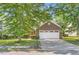 Traditional brick home with a two-car garage, mature trees, and green lawn at 484 Cathedral Dr, Mcdonough, GA 30253