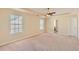Spacious main bedroom with carpet, natural light from two windows, ceiling fan, and ensuite bathroom at 484 Cathedral Dr, Mcdonough, GA 30253