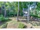 View of the backyard with mature trees and a charming cottage-style house in the background at 850 Old Spring Way, Sugar Hill, GA 30518