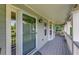 A view of the covered porch, featuring a door, several windows, and a gray wood floor at 850 Old Spring Way, Sugar Hill, GA 30518