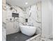Modern bathroom featuring marble walls, a freestanding tub, and a sleek shower with herringbone tile flooring at 550 Stewart Nw Ave, Marietta, GA 30064