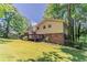 Backyard view of a two-story home with lush lawn, mature trees, a rear deck, and brick accent at 4016 Nations Dr, Douglasville, GA 30135