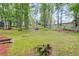 Grassy backyard surrounded by mature trees with small stone steps in the landscape at 2055 Timberland Dr, Cumming, GA 30040