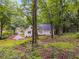 Landscaped backyard with patio area and grassy lawn featuring mature trees at 2055 Timberland Dr, Cumming, GA 30040