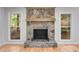Stone fireplace with wooden beam mantel, flanked by windows with backyard views at 2055 Timberland Dr, Cumming, GA 30040